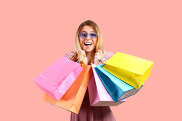 Fototapeta premium Black friday season sale concept. Attractive young woman with long blonde hair, wearing sexy pink dress, holding many different blank shopping bags. Bright isolated background, copy space, close up.