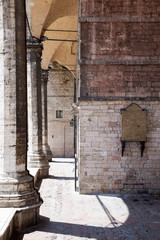 Photograph of the exterior of the Cathedral of San Lorenzo in Perugia, Italy; columns with arches and shadows.