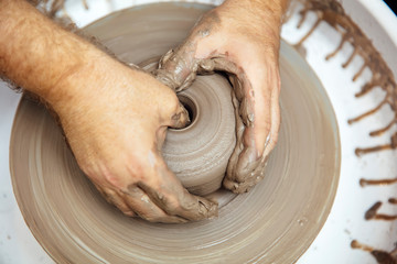 View at an artist makes clay pottery on a spin wheel