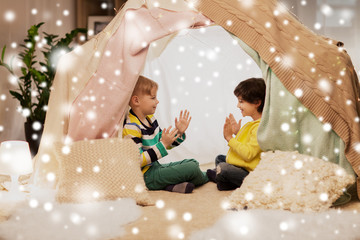 childhood, christmas and friendship concept - happy boys playing clapping game in kids tent or...
