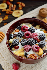 Granola with yougurt, nuts, fresh berries on wooden brown background