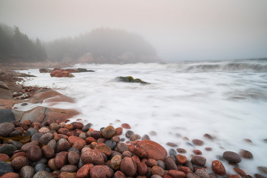 Long exposure of waves crashing on colourful pink rocks, Black Brook Cove Beach, Cape Breton, Nova Scotia, Canada