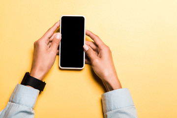 cropped view of woman holding smartphone with blank screen on orange