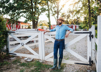 A portrait of farmer standing outdoors on family farm. Copy space.