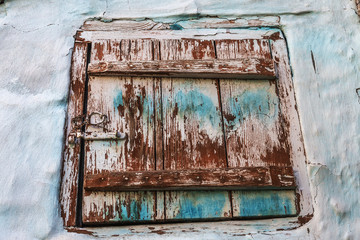 Single wooden door in an old city wall. Closed vintage wooden door with a lock. The texture of the old door, which peels off with old paint