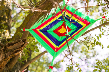 Tibetan mandala knitting with thread on the branches of a green tree.