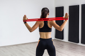 Back side portrait of sporty woman wearing in black top and leggings performs exercises for the...