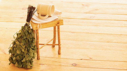 Obraz na płótnie Canvas Pampering and relaxing in the sauna. Accessories for a steam room, wooden furniture, a bath broom and water in a mug. Copy spase