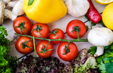 Vegetables and greens on wooden background. Pepper, dill, garlic, lemon, cherry tomatoes.
