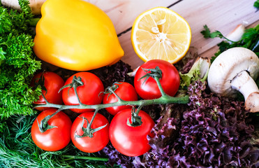 Vegetables and greens on wooden background. Pepper, dill, garlic, lemon, cherry tomatoes.