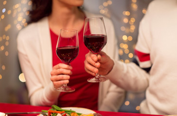holidays, family and celebration concept - close up of happy couple having christmas dinner at home and drinking red wine