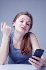 Naklejka premium Wasting time on social media. Portrait of young beautiful woman with smartphone as symbol of social Media addiction. Psychological problems and media mania concept.