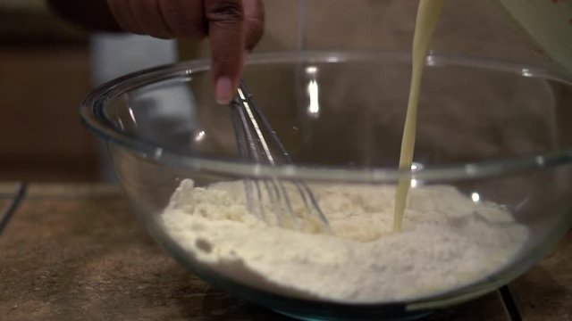 Whisking liquid ingredients into flour and dry baking ingredients, Close Up