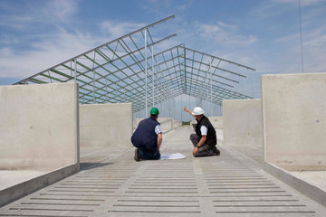 Architect and builder in discussion with building plan. Building a cattle stable. Building site. Netherlands. Construction site.