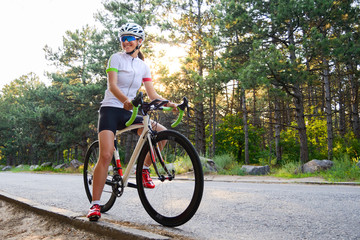 Portrait of Young Woman Cyclist with Road Bicycle on the Road in the Summer Forest. Healthy Lifestyle Concept.