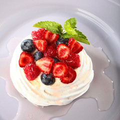 Pavlova dessert Bizet cake with fresh fruits. dessert concept in a restaurant or cafe. Photo from above. White plate on a black background.