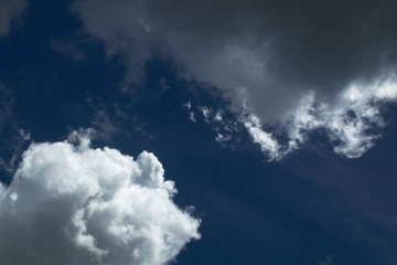 Blue sky cutting through at an angle dividing bright clouds from dark clouds.