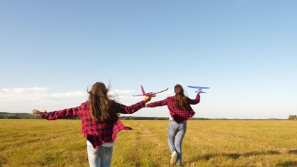 children play toy airplane. teenagers want to become pilot and astronaut. Happy girls run with toy plane at sunset on field. concept of happy childhood. Girls dream of flying and becoming a pilot.