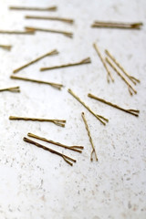 Gold colored hair pins on a marble background. Selective focus.