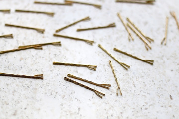 Gold colored hair pins on a marble background. Selective focus.