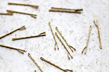 Gold colored hair pins on a marble background. Selective focus.