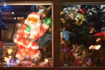 Santa Claus with gifts in the festive windows. New Year holiday.