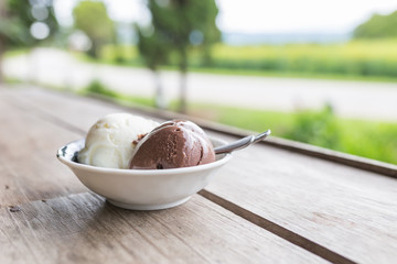 Bowl of various colorful ice cream balls on wooden background.