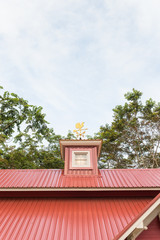 Chicken wind measure direction on the top of roof against blue sky.