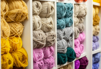 Knitting needles, colorful threads. Knitting pattern of colorful yarn wool on shopfront. Knitting background. Knitting yarn for handmade winter clothes. Colorful background with yarn ball. - obrazy, fototapety, plakaty