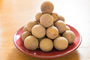 Fresh longan on a red porcelain plate isolated
