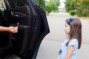 Stranger in the car offers candy to the child. Kids in danger. Children safety protection kidnapping concept