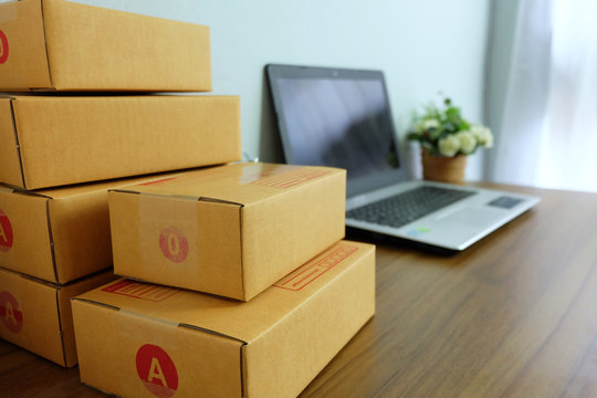 Laptop Computer And Product Box Or Shipping Parcel Box On Wooden Table, Online Shopping, Work At Home, E Commerce