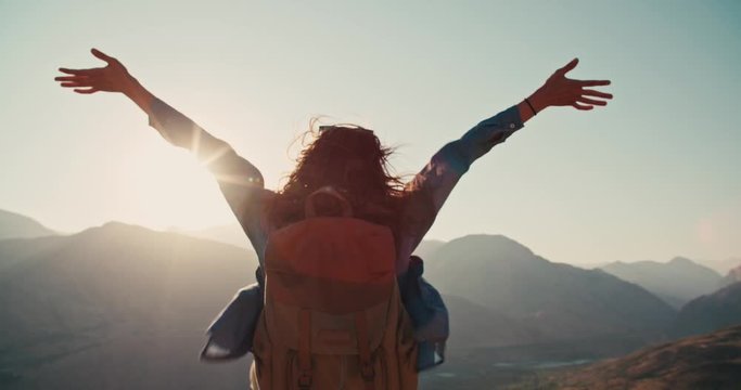Young girl standing on top of mountain and victoriously raising hands up, looking far away - zennism, freedom, adventure concept 4k footage