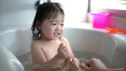 Cute Little child Having a Bath,Wash hair by Mom's hands washing  Asian girl head in the bathroom. The symbol of purity and hygiene education