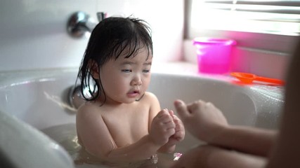 Cute Little child Having a Bath,Wash hair by Mom's hands washing  Asian girl head in the bathroom. The symbol of purity and hygiene education