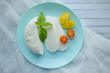 Home-made sliced Adyghe cheese lying on wooden board.