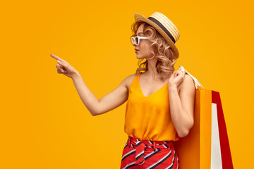 Woman with shopping bags pointing aside