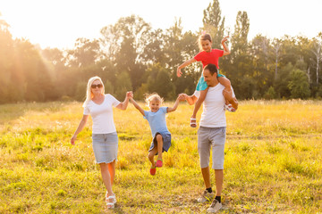 Fototapeta premium young familiy running through a yellow field