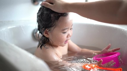 Cute Little child Having a Bath,Wash hair by Mom's hands washing  Asian girl head in the bathroom. The symbol of purity and hygiene education