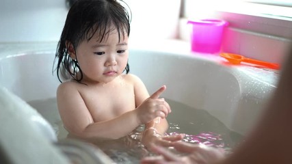 Cute Little child Having a Bath,Wash hair by Mom's hands washing  Asian girl head in the bathroom. The symbol of purity and hygiene education