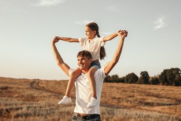 Joyful little girl sitting on shoulders of father