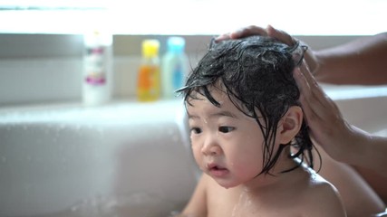 Cute Little child Having a Bath,Wash hair by Mom's hands washing  Asian girl head in the bathroom. The symbol of purity and hygiene education