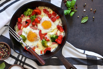 Fried eggs with tomatoes, peppers and broccoli for breakfast on the kitchen table. Good morning.