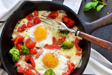 Fried eggs with tomatoes, peppers and broccoli for breakfast on the kitchen table. Good morning.