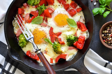 Fried eggs with tomatoes, peppers and broccoli for breakfast on the kitchen table. Good morning.