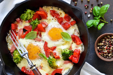Fried eggs with tomatoes, peppers and broccoli for breakfast on the kitchen table. Good morning.