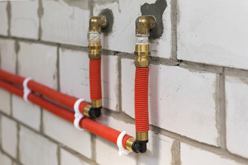 Plumbing pipes for water supply on a white brick wall during construction and repair