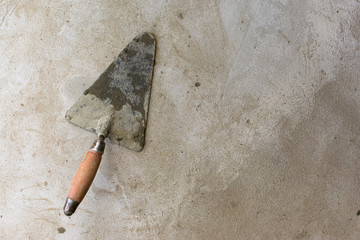 Construction tool for repairing trowels lies on gray-brown cement and concrete