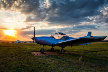 Fototapeta na wymiar A small sports airplane parked at the airfield at scenic sunset