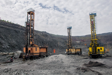 Three high-power drilling rigs drill holes in the iron ore quarry for falsely laying explosives in it.